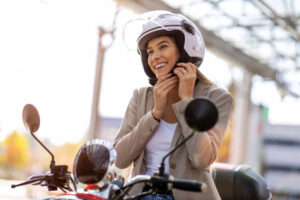 Une femme sur une moto en train de mettre son casque.